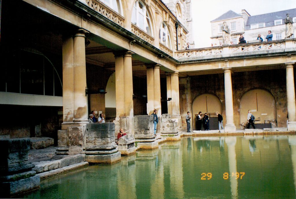 Image shows green water in foreground, surrounfed by decorative walkways and columns.