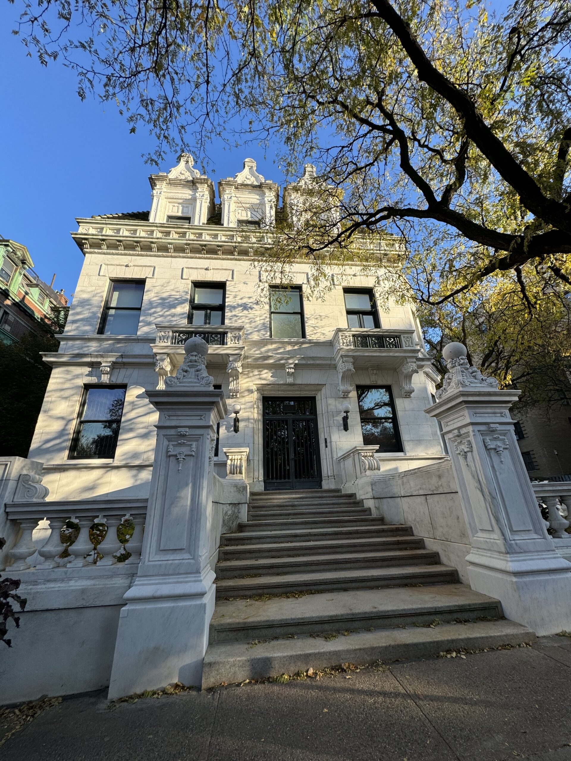 Three level mansion with Dormer windows painted white with the large tree out the front