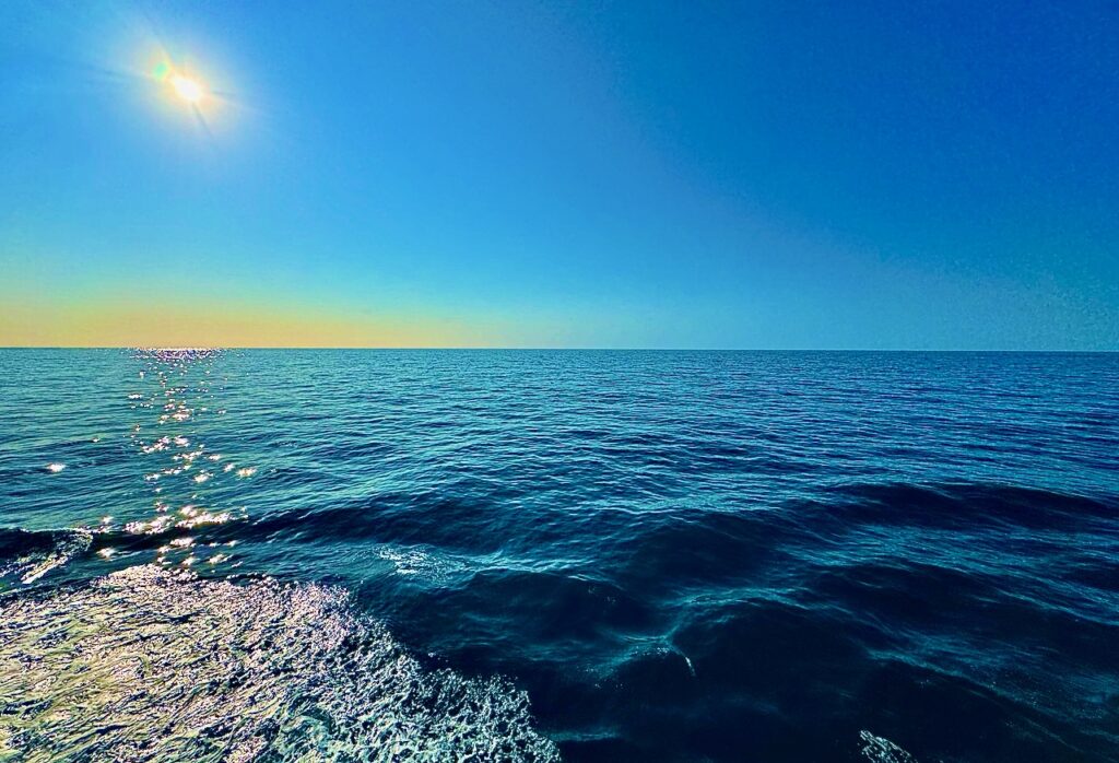 I image from our balcony of a book in the ocean the sun is high in the sky and the ocean is calm