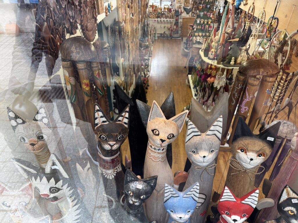 Wood carved cats of all colours in a shop winfow