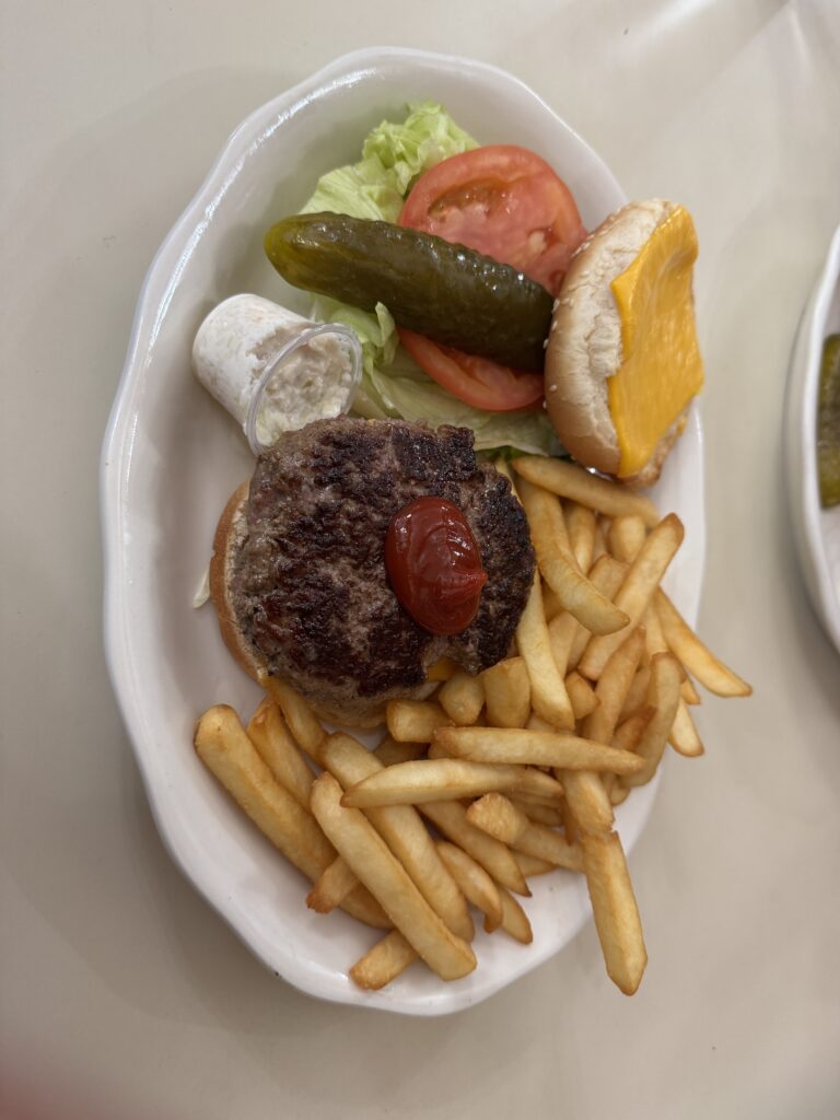 Lunch, chips and a burger in two pieces, meat patties, salad and cheese on a bun