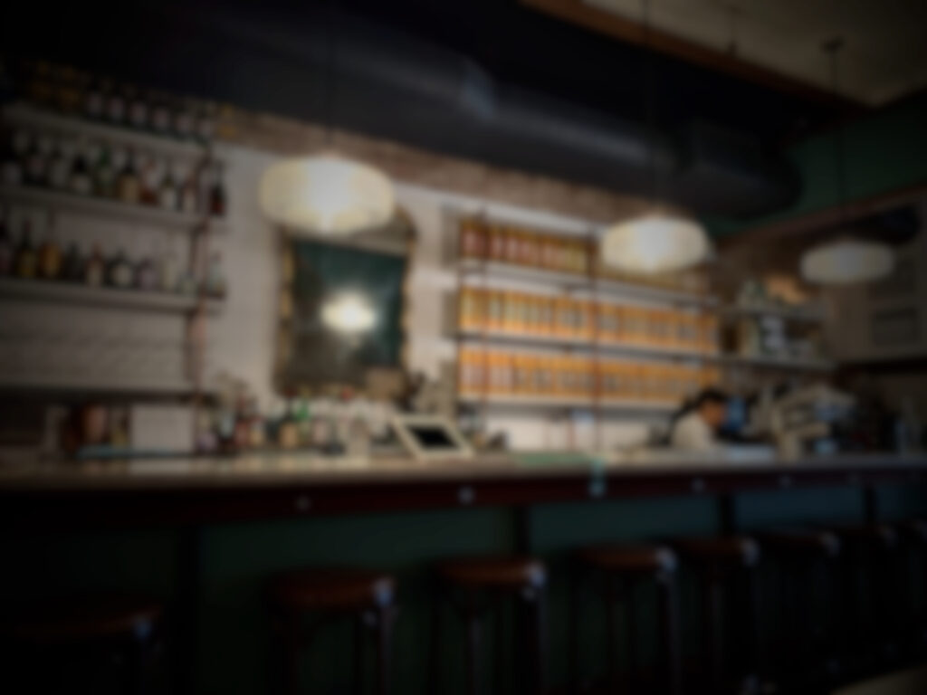 Blurred image of restaurant serving counter. Bottles of alcohol and tea are in the background.